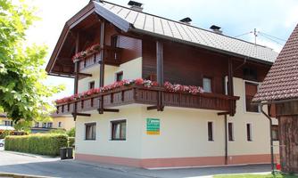 A modern house with a ground floor and a balcony. The balcony is decorated with colorful flowers.