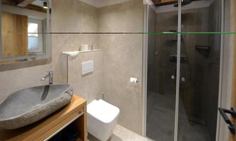 A modern bathroom with mineral walls and an elegant shower. The stone sink and wooden elements give the room a natural look.