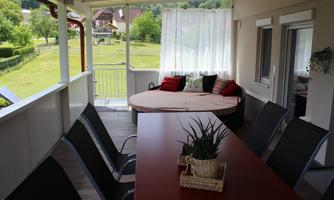 An inviting terrace with a round seating area and a large table. The view of the green landscape creates a relaxed atmosphere.