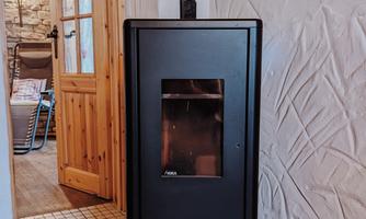 A modern fireplace stands in a cozy room. The fireplace is black and has a large glass front.