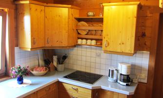 A cozy kitchen with wooden cabinets and bright tiles. On the countertop, there is a coffee machine and a bouquet of flowers.
