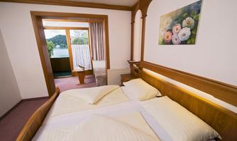 A cozy bedroom with a large bed and bright wooden design. Through the window, there is a beautiful view of nature.