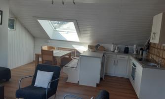 A bright and modern penthouse apartment with an open kitchen and a dining area. Large windows provide plenty of daylight.