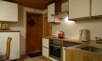 A cozy kitchen with wooden paneling and modern appliances. The room is bright and inviting.