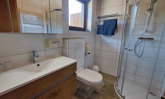A modern bathroom with a shower and a sink. Bright tiles and wooden elements create an inviting atmosphere.