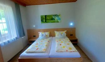 A cozy bedroom with a double bed and colorful bedspreads. Large windows provide plenty of daylight and a relaxed atmosphere.