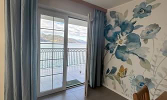 A cozy room with large windows and a blooming mural. The view leads to a beautiful outlook to the outside.