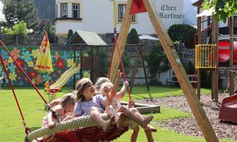 A playground with a swing and colorful play equipment. Three children are enjoying their time outdoors.