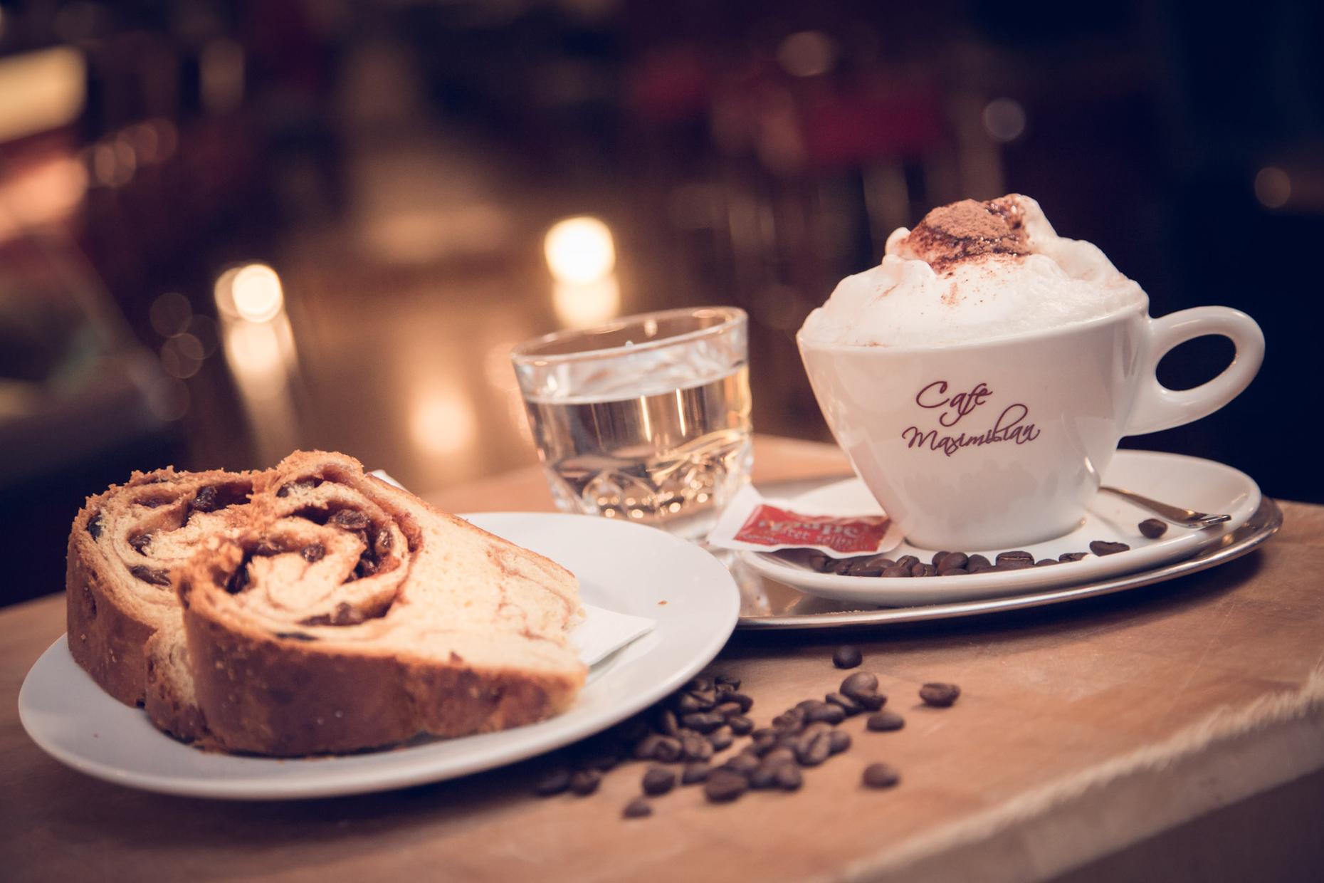 Kaffee und Strudel im Café Maximilian Wien mit Glas Wasser und Kaffeebohnen