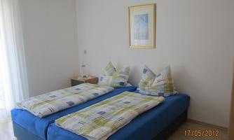 A bright bedroom with two single beds. The bedding is colorful and the walls are painted in neutral colors.