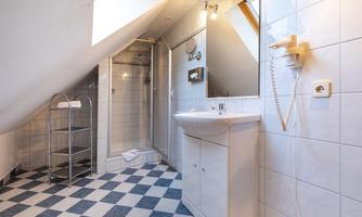 A modern bathroom with shower and sink. The floor is designed in a black-and-white checkerboard pattern.