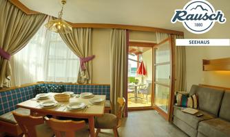 A cozy living area with a dining table and elegant chairs. Large windows allow plenty of daylight and show access to a balcony.