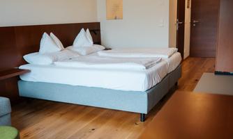 A modern room with a double bed and two pillows. The room has a wooden floor and a cozy seating area.
