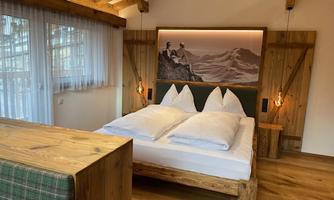 A cozy bedroom with a large bed and rustic wooden decor. Bright colors and natural materials create an inviting atmosphere.