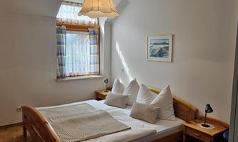 A cozy bedroom with a double bed and bright colors. The window lets in plenty of daylight, and the room is simply but invitingly furnished.