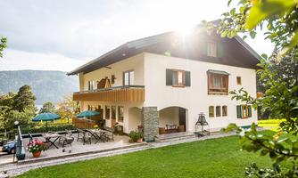 A beautiful house with a balcony and terrace in a green environment. The sun is shining, creating a pleasant atmosphere.