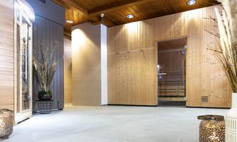 A modern sauna area with wooden paneling and soft lighting. Decorative plants and stylish lanterns are present in the room.