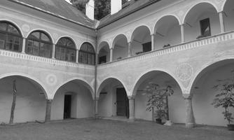 A shady courtyard with elegant arches and windows. The atmosphere is calm and historic.