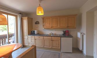 A bright kitchen with wooden cabinets and modern appliances. Large windows let in plenty of daylight.