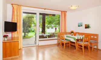 A bright and inviting living room with a dining area. Large windows provide a view of the garden.