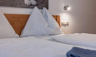 A cozy bedroom with two beds covered with white pillows and bedding. A picture of a cat hangs on the wall.