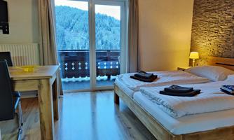 A cozy room with two beds and a balcony with mountain view. The wood style creates a warm and relaxed atmosphere.