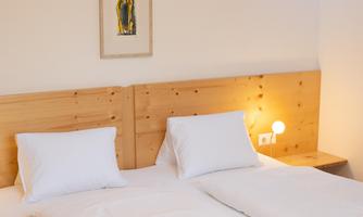 A bright bedroom with a double bed and two pillows. A decorative picture is hanging on the wall.