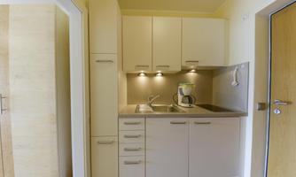 A modern kitchen with bright cabinets and a stone countertop. The kitchen is well-equipped with a sink and a coffee pot.