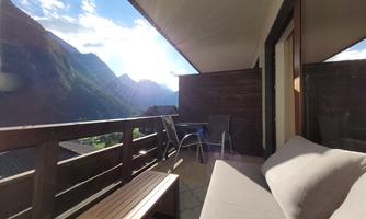 A cozy balcony with a view of the mountains. A sofa and a table invite you to relax.