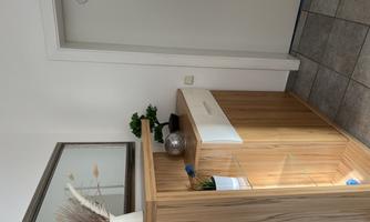 A bright entrance area with modern wooden furniture. Inside are plants and a decorative vase as well as a mirror.