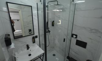 A modern bathroom with a glass shower and stylish fixtures. The walls have an elegant marble look.