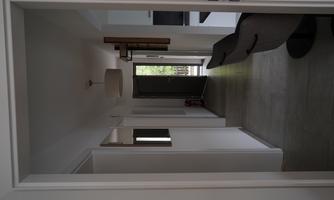 A bright hallway with modern walls and an open entrance. On the right side, chairs and a television are visible.
