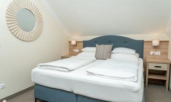 A modern bedroom with a large double bed and cozy pillows. A round mirror hangs on the wall, making the room bright and inviting.