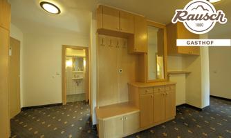 A bright room with wooden cabinets and a mirror. The floor has a carpet with a subtle pattern.
