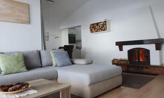 A modern living room with a comfortable sofa and a beautiful fireplace. The room has a bright, welcoming atmosphere.