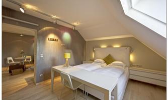 A modern bedroom with a double bed and a desk. The walls are painted in soft colors, and there is pleasant lighting.
