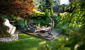 Two swinging chairs surrounded by lush greenery and trees.