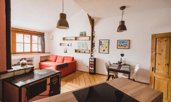 A modern living room with a red sofa and a dining table. Bright walls and wooden floors create an inviting atmosphere.