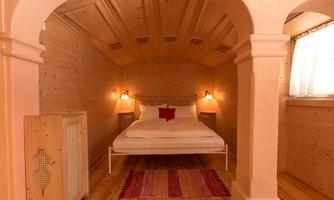 A cozy bedroom with wooden paneling and a double bed. The warm colors and soft lighting create an inviting atmosphere.