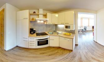 A modern kitchen with bright cabinets and a stove. It is well-equipped and has an open living area.