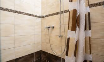 A modern shower cabin with bright tiles and a shower curtain. The shower is clean and functionally furnished.