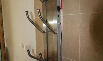 A modern coat rack made of stainless steel with multiple hooks hangs on a wall. It provides space for jackets and coats.
