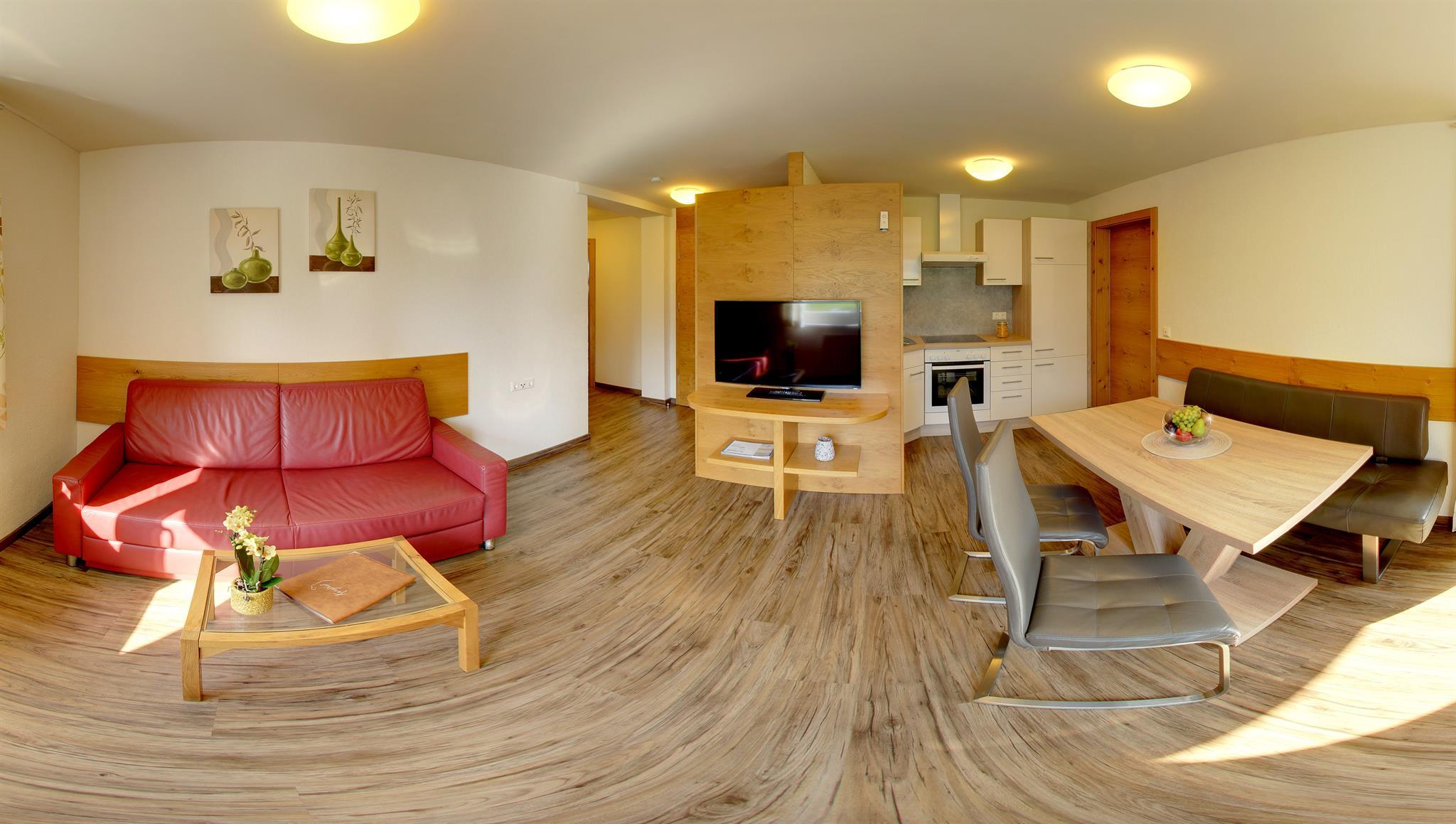 A modern living room with a red sofa and dining table. The room has wooden floors and a bright, inviting atmosphere.