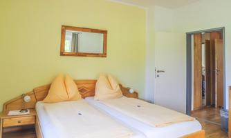 A bright room with two single beds and a large mirror. The walls are painted in a soft shade of yellow.