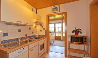 A modern kitchen with bright cabinets and a cook-friendly ambiance. Light-flooded access to a cozy lounge area.