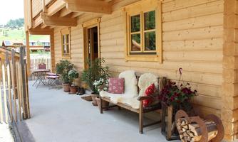 An inviting entrance area of a wooden house with a cozy bench, potted plants, and a wood storage. The space exudes a rustic and relaxed atmosphere.