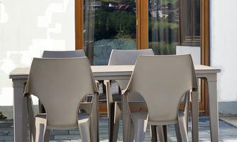A modern table with chairs on a terrace. In the background, there are large windows that allow a view outside.