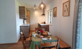 A cozy dining area with a table set for breakfast. The bright kitchen and wood details give the room an inviting atmosphere.
