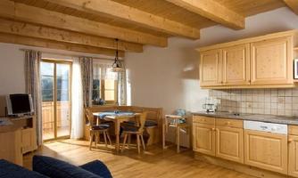 A bright and welcoming apartment with an open living and kitchen area. The furnishings consist of wood and provide a cozy dining area as well as access to a balcony.