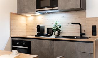 A modern kitchen with wood and stone elements. It includes a stove, a microwave, and a coffee maker.